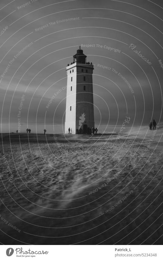 Ein Leuchtturm in einer Sanddüne von Menschen Umgeben. Sanddünen sanddüne Schwarzweißfoto schwarz sandig mystisch zeitlos Einsamkeit Abenteuer Dänemark Wind