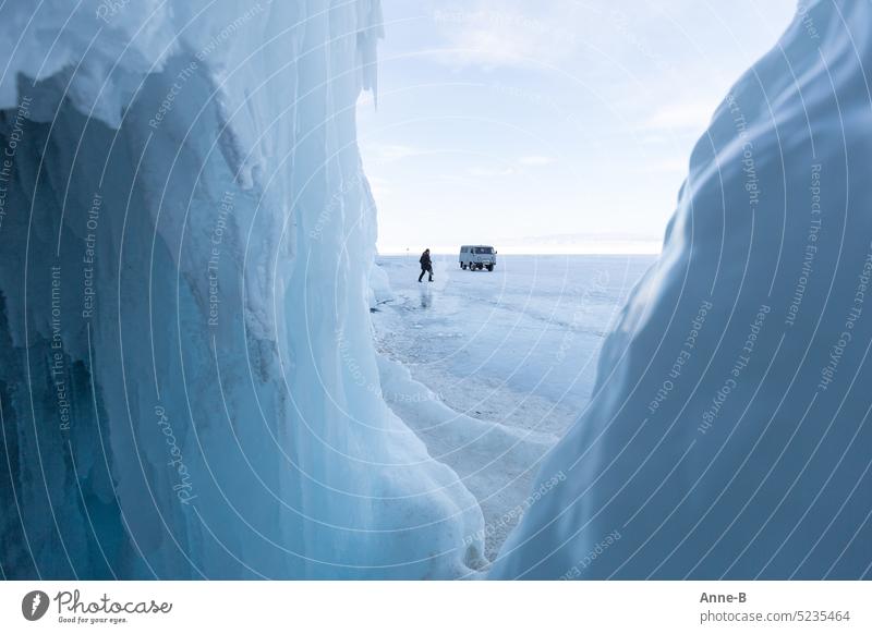 schön kalt auf dem Baikalsee, Blick aus einer Höhle auf die Eisfläche auf der ein Mensch und ein Auto zu sehen ist. eisig blau frostig Auto auf dem Eis