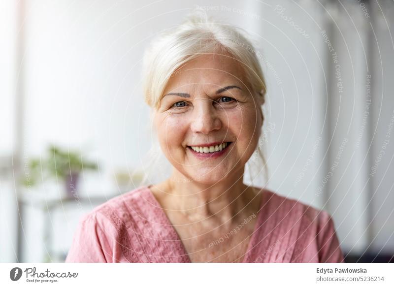 Porträt einer lächelnden älteren Frau, die in die Kamera schaut echte Menschen Senior im Innenbereich Loft Fenster heimwärts reifer Erwachsener eine Person