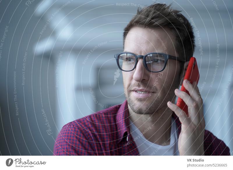 Nachdenklicher junger deutscher Geschäftsmann mit Brille, der ein dringendes Gespräch am Mobiltelefon führt Deutsch Österreicher Mann Mobile Telefon Typ