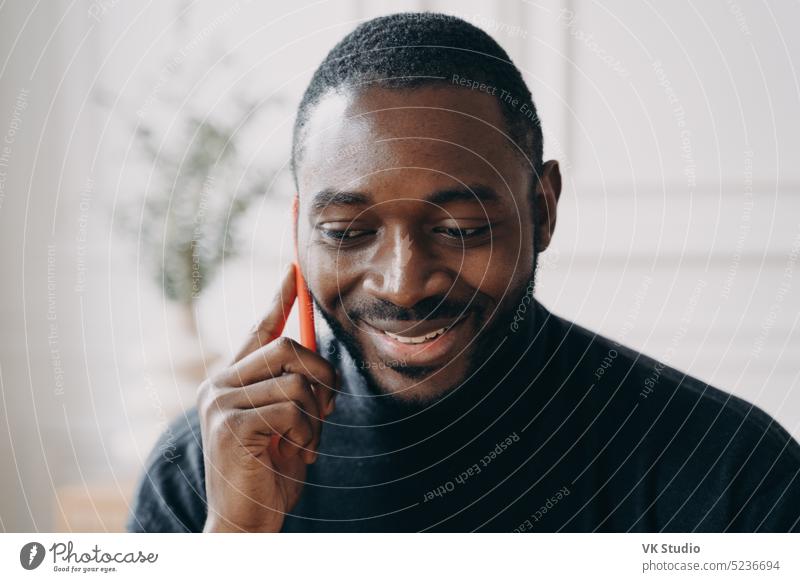 Fröhlicher junger afroamerikanischer Geschäftsmann, der mit seinem Smartphone spricht, während er zu Hause in der Ferne arbeitet Afrikanisch Amerikaner Mann