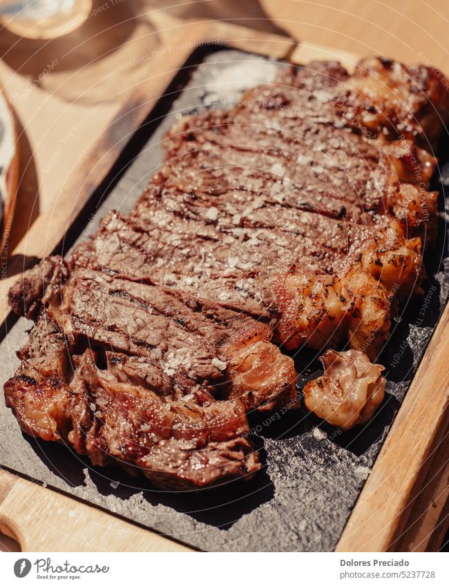 Gegrilltes Ribeye-Steak auf Holzbrett. Gegrilltes Fleisch mit Sauce. Hintergrund Barbecue grillen Rindfleisch Beefsteak schwarz Holzplatte gekocht