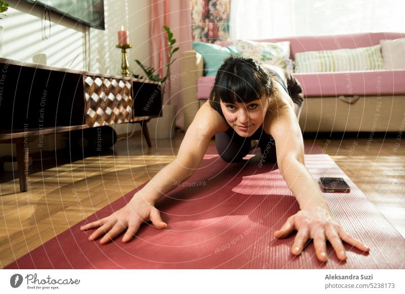 Schöne Frau übt Yoga zu Hause. Stilvolle gemütliches Zuhause Interieur. Doing Yoga-Übungen und genießen Sie den frühen Morgen. Close-up-Porträt von lustigen Winkel. Gesunder Lebensstil