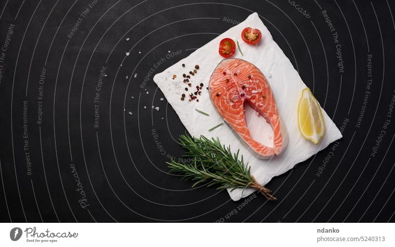 Rohes Lachssteak auf einer weißen Tafel, Zitronenscheiben, Gewürze. Draufsicht auf schwarzen Tisch roh Fisch Lebensmittel Spielfigur frisch Hintergrund