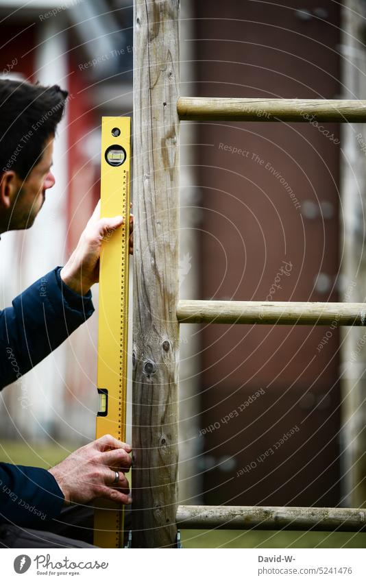Heimwerker mit Wasserwaage an einem Klettergerüst Garten Werkzeug kontrollieren Handwerker Arbeit & Erwerbstätigkeit bauen Mann