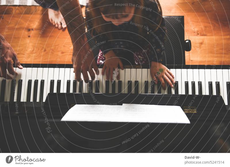 Vater und Tochter spielen zusammen Klavier Kind Musik musikalisch Kindererziehung Musiker musizieren Spaß Freude beibringen erklären zeigen Musikinstrument