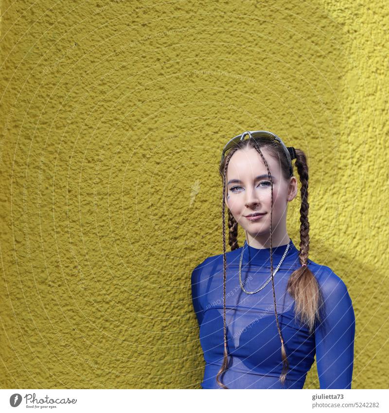 Teenagerin der Generation Z - gestylt mit Zöpfen in coolem, blauen Techno Outfit vor gelber Wand Lieblingsmensch 18-20 Jahre Netzshirt Kaukasier technomusik