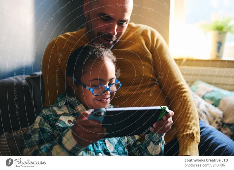 Fröhlicher Junge mit Down-Syndrom spielt Computerspiel mit seinem Vater heiter Sohn Lifestyle rassenübergreifend Glück Lächeln spielen Video Spiel Mann Kind