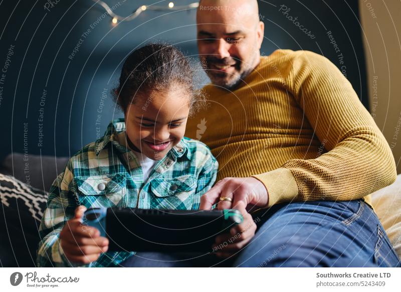 Junge mit Down-Syndrom lächelt und spielt mit seinem Vater ein Computerspiel Sohn Lifestyle Lächeln rassenübergreifend spielen Video Spiel Mann Glück heiter