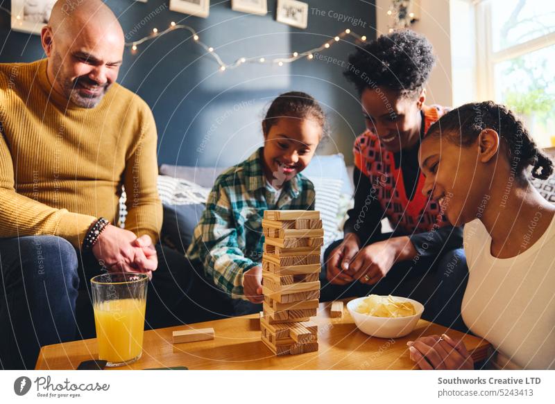 Junge mit Down-Syndrom spielt mit seiner Familie zu Hause ein Brettspiel Spiel spielen rassenübergreifend Lifestyle Vater Mutter Mädchen