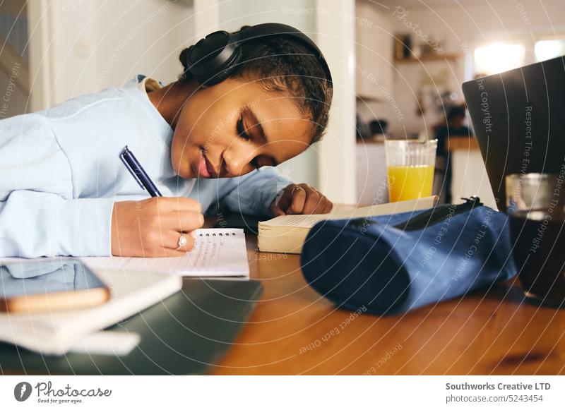 Teenager-Mädchen macht Hausaufgaben und trägt Kopfhörer lernen Zelle Handys zuhören Konzentration schreiben Notebook Schreibstift anhaben Buch Lernen Bildung