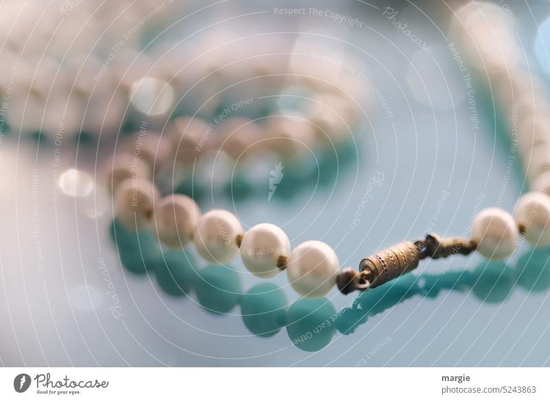Perlenkette mit Verschluss perlen Nahaufnahme Menschenleer Makroaufnahme Licht Reflexion & Spiegelung Schatten Schmuck unscharf unscharfer Hintergrund blau