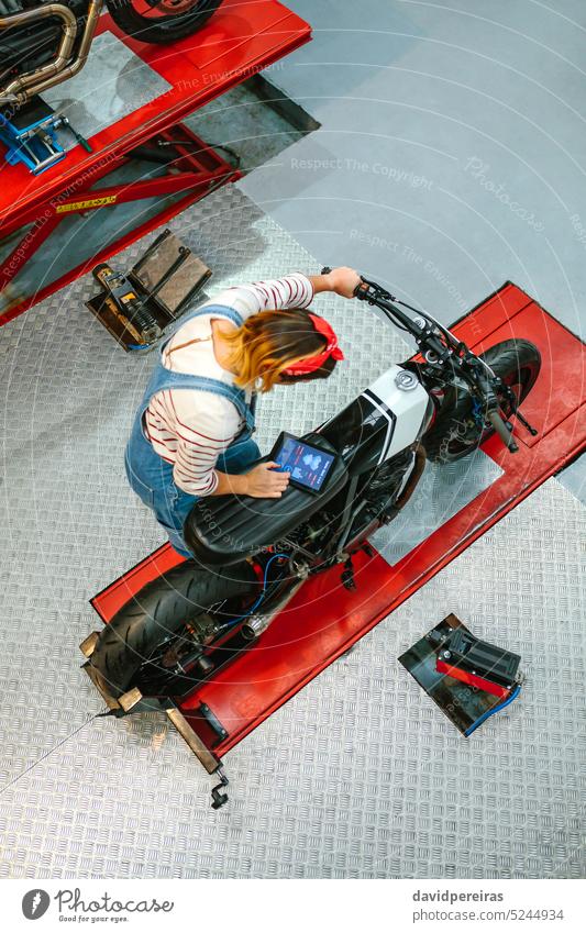 Mechanikerin nutzt Diagnose-App, um individuelles Motorrad zu überprüfen Frau benutzend Anwendung Diagnostik Tablette digital Überprüfung überblicken Fabrik