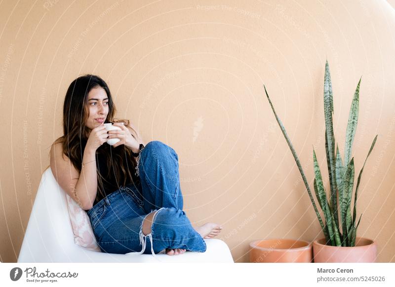barfüßige junge Frau in Freizeitkleidung entspannt sich mit einer Tasse Kaffee auf der orangefarbenen Terrasse Barfuß Übergewicht Freizeitbekleidung Tag