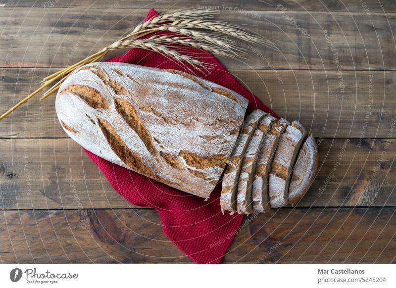 Ein Stück rustikales Brot auf einem hölzernen Hintergrund mit Ornamenten aus Weizenähren. Platz zum Kopieren. Lebensmittel Spielfigur Müsli Ohren