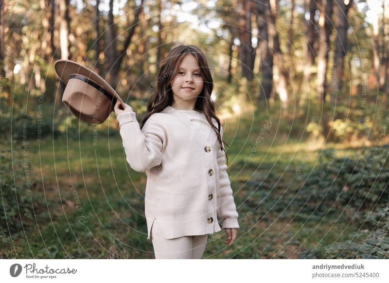 Porträt des schönen kleinen Mädchens in Hut schaut in die Kamera und lächelnd. Happy niedlichen Kind mit Spaß im Park im Freien, genießen die Kindheit, in guter Stimmung sein. Traum von Kind und Glück des Kindes