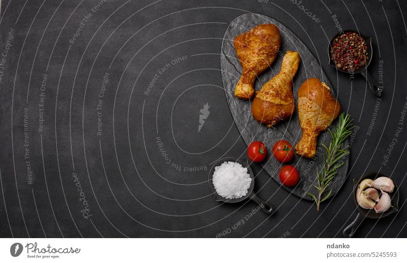 Rohe Hähnchenschenkel in Gewürzen auf einem schwarzen Brett, Draufsicht. Garen mit Gewürzen Bein Fleisch roh Tomate Paprika Knoblauch Abendessen Vogel
