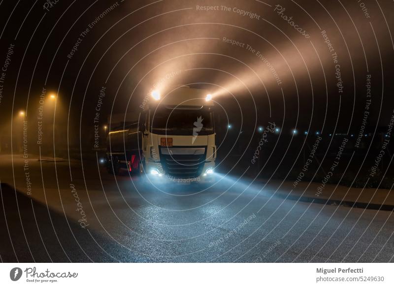 Tankwagen mit Gefahrgut in einer nebligen Nacht mit eingeschaltetem Fernlicht. Lastwagen Lichter Weitreichende Nebel Straße Vorrat logistisch Verkehr Dunkelheit