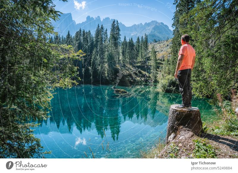 Ein erwachsener Mann bewundert die wunderbare Berglandschaft mit dem türkisfarbenen Wasser des Karersees und der Silhouette der Gipfel der Latemar-Gruppe im Hintergrund.Dolomiten, Italien