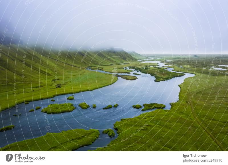 Island. Blick aus der Luft auf Berg, Feld und Fluss. Landschaft in Island in der Tageszeit. Blick von einer Drohne. Sommer. Bewölktes Wetter. Frisches Gras auf einem Feld. Reisen und Urlaub Bild