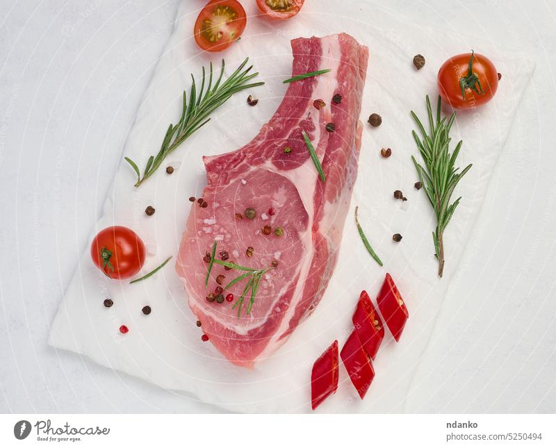 Rohe Schweinelende am Knochen und Gewürze auf weißem Hintergrund. Portion für Mittag- und Abendessen, Ansicht von oben roh rot Rosmarin Fleisch Schweinefleisch