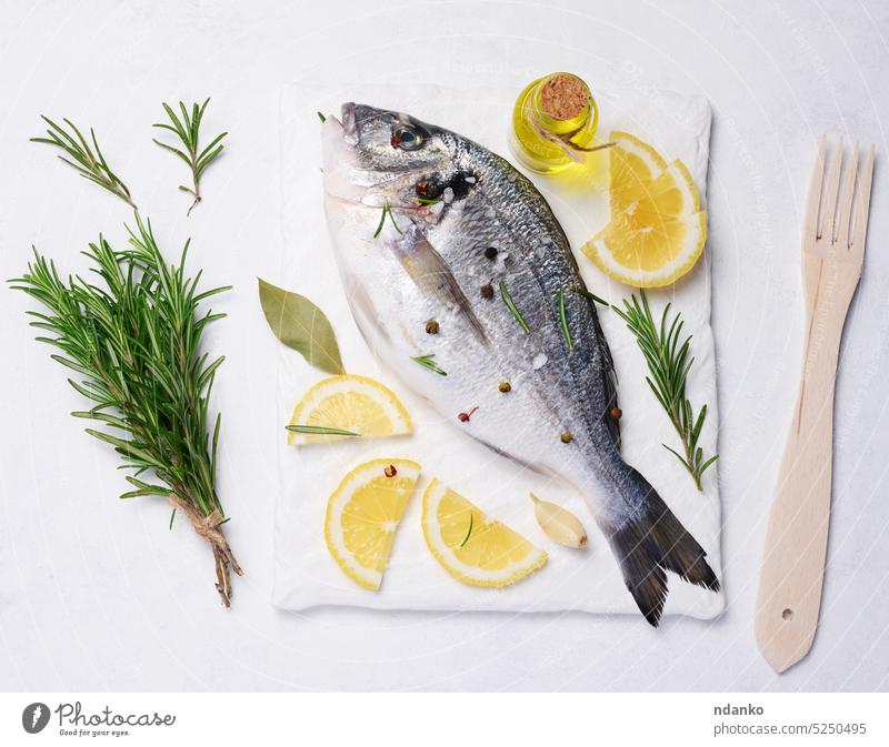 Roher ganzer Goldbrassenfisch auf weißem Brett und Gewürze zum Kochen, Draufsicht auf weißem Tisch roh Dorado Fisch Meeresfrüchte Essen zubereiten Rosmarin Salz