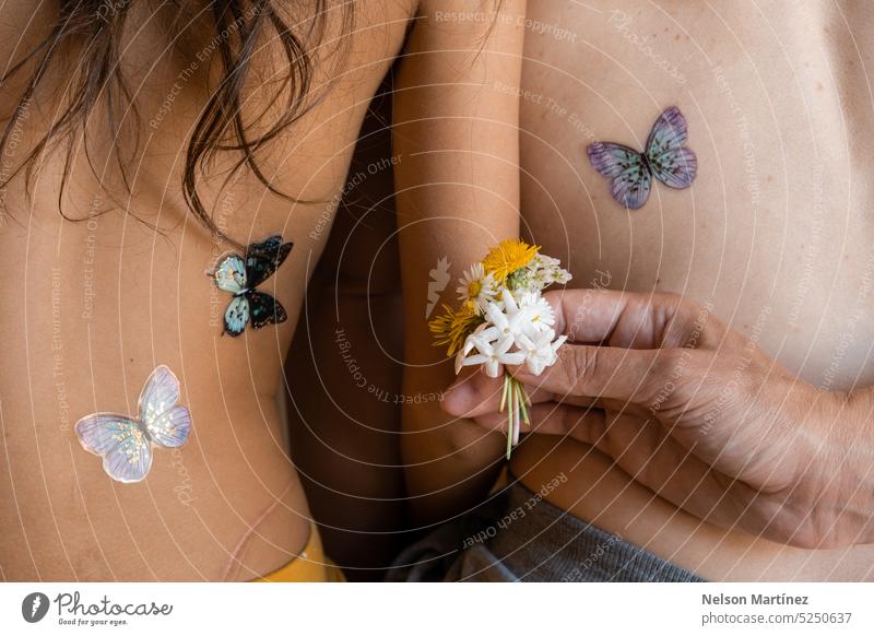 Mutter und Tochter von hinten mit Schmetterlings-Tattoo-Aufklebern auf dem Rücken. menschliche Beziehungen Mutterschaft im Innenbereich blond positiv eltern