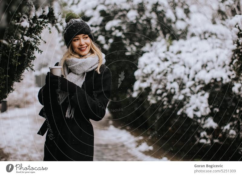 Junge Frau in warmer Kleidung genießt den Schnee mit einer Tasse Kaffee zum Mitnehmen Erwachsener Air allein schön Schönheit brünett Verschlussdeckel charmant