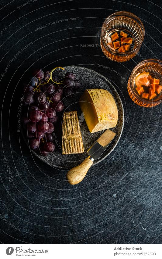 Schwarzer Steinteller mit Käse und rohen leckeren Trauben Amuse-Gueule Sortiment Hintergrund Kuh Besteck Schneidebrett Molkerei dunkel essen fermentiert