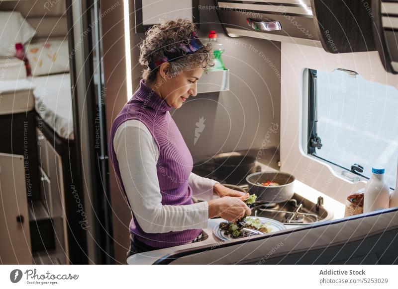 Konzentrierte Frau kocht gesundes Essen im Wohnwagen geschnitten Salat Koch Salatbeilage selbstgemacht Gemüse Lebensmittel Wohnmobil Kleintransporter positiv