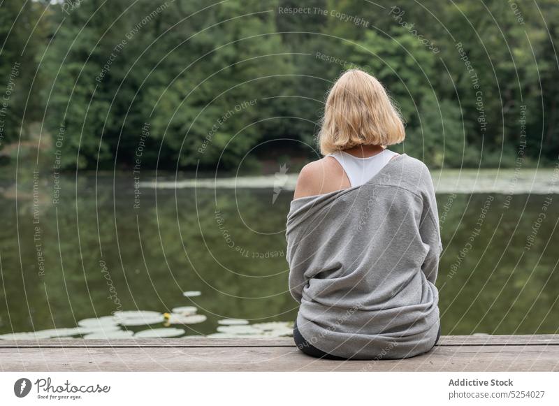 Frau sitzt auf einem Steg in der Nähe eines Teiches Pier Lotosblatt Umwelt sich[Akk] entspannen friedlich ruhig Harmonie Wasser Natur Lebensmitte genießen See