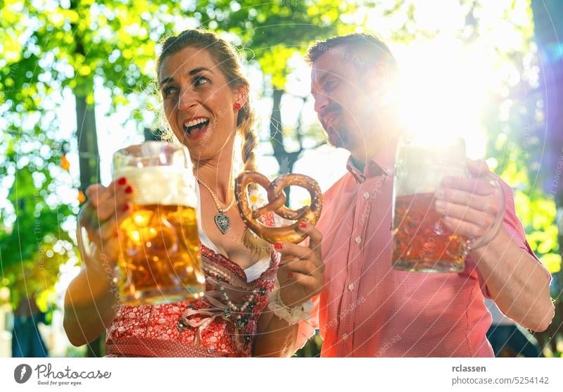 Happy Couple im Biergarten oder beim Oktoberfest feiern und ein Glas Bier und die Sonne genießen Mann Frau Liebe Paar Brezeln Flirten Besteck bayerisch