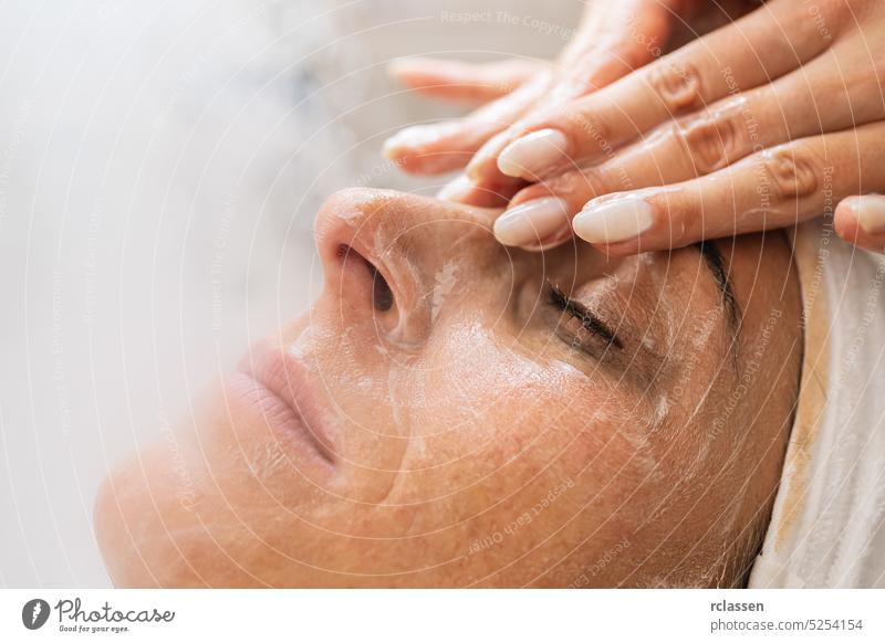 Schönheitsbehandlung des Gesichts mit Ozon-Gesichtsdampfer und Creme-Massage mit den Händen in einem Schönheitszentrum oder Kosmetiksalon. Sahne Verdunstung