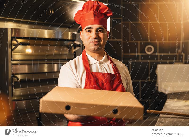 italienischer Pizzabäcker hält Paketpizza in einer Schachtel für die Lieferung in einer italienischen Pizzeria Rudel Schürze geschmackvoll kitschig Kasten Mann