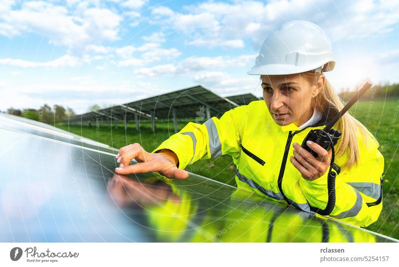 Weiblicher Ingenieur schaut skeptisch auf ein Solarpanel und hält ein Walkie Talkie zur Kommunikation. Nachhaltige Energie und Solarenergie Feld Konzept Bild