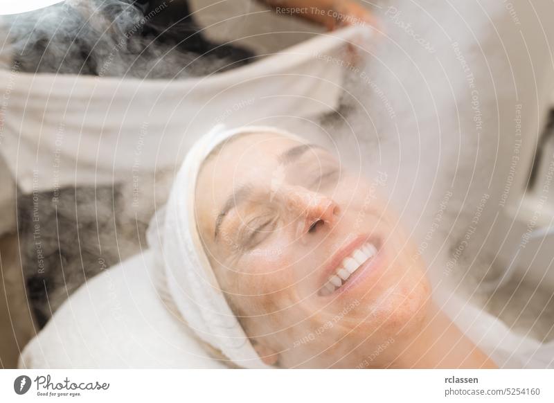 Bedampfen der Gesichtshaut einer glücklichen Frau vor der Reinigung der Haut in einem Kosmetiksalon Massage Sahne Verdunstung Handtuch Therapie
