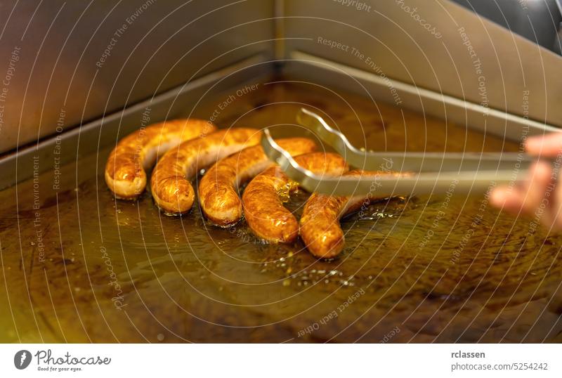 Mann brät Currywurst Wurst auf einer Bratplatte Restaurant Berlin Junk Food Wurstwaren Essen Bratwurst Kalorien Großstadt Diät Fett gebraten Deutschland heiß