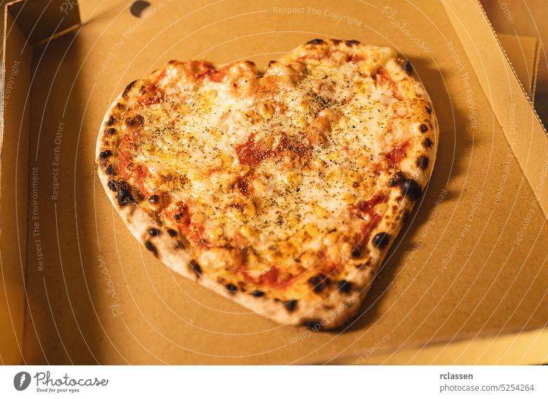 Frische italienische Pizza in Herzform aus dem Steinofen in einer Schachtel Thunfisch italienische Pizzeria Symbol Zeichen Lächeln Liebe geschmackvoll kitschig