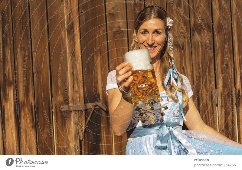 Frau auf dem Oktoberfest in traditioneller bayerischer Tracht, die einen Bierkrug in einem bayerischen oder Biergarten mit Kopierraum hält gold Party Restaurant