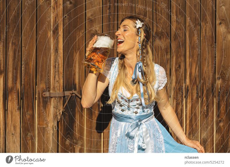 Frau auf dem Oktoberfest in traditioneller bayerischer Tracht trinkt Bier aus einem großen Krug in einem bayerischen oder Biergarten gold Party Restaurant