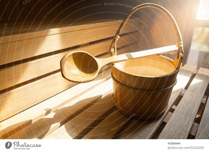 Holzlöffel mit Wassereimer mit für das Aufgießen von Wasser auf heiße Steine in der finnischen Sauna, Spa und Warmwasserbad-Therapie Konzeptbild. Sauna-Zubehör in einer Sauna.