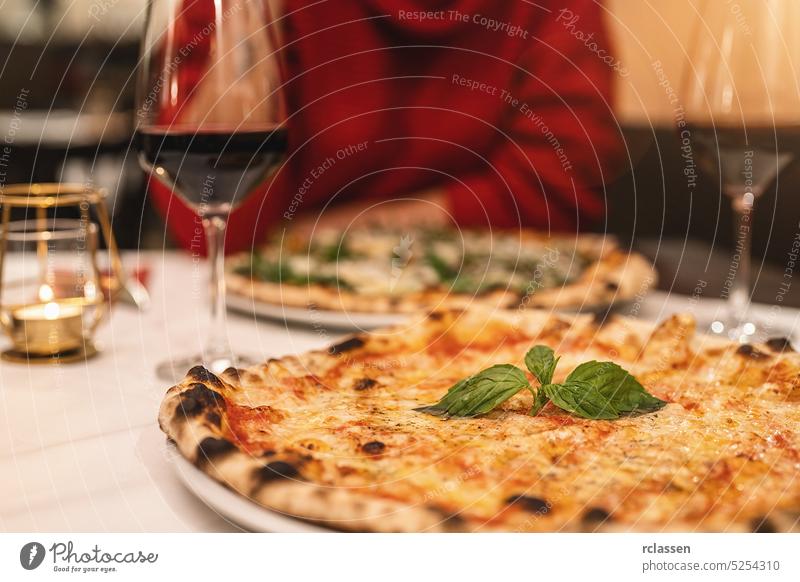Menschen, die in einem italienischen Restaurant Rotwein trinken und Margherita-Pizza mit Basilikum essen margherita Paar Rendezvous Scheibe Käse Essen London