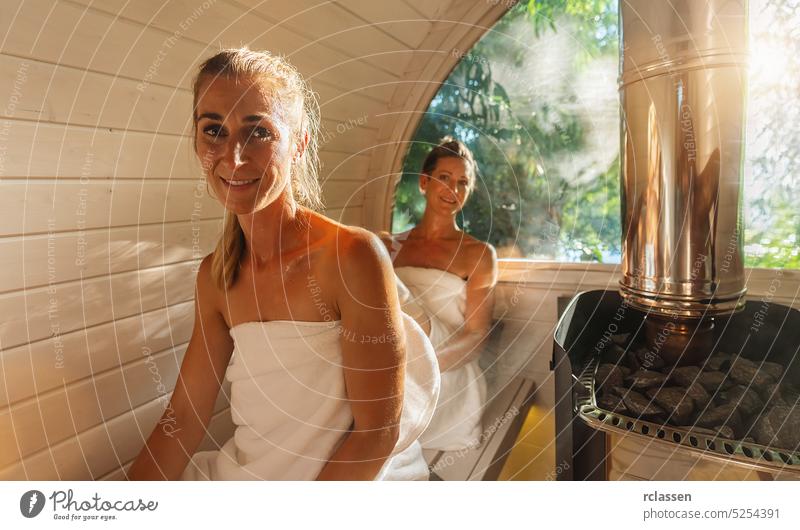 Entspannte Frau und ihre Freundin in der Holzfass-Sauna im Sommer in Norwegen. Genießen Sie Ihren Urlaub beim Entspannen in der finnischen Saunakabine. Freunde