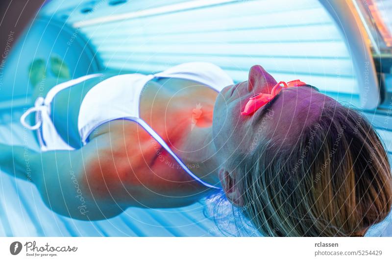 Entspannende Frau im Solarium mit Brille beim Bräunen Bett Salon Licht Haut ultraviolett Mädchen sich[Akk] entspannen Menschen Spa Gesundheit Schönheit Glück