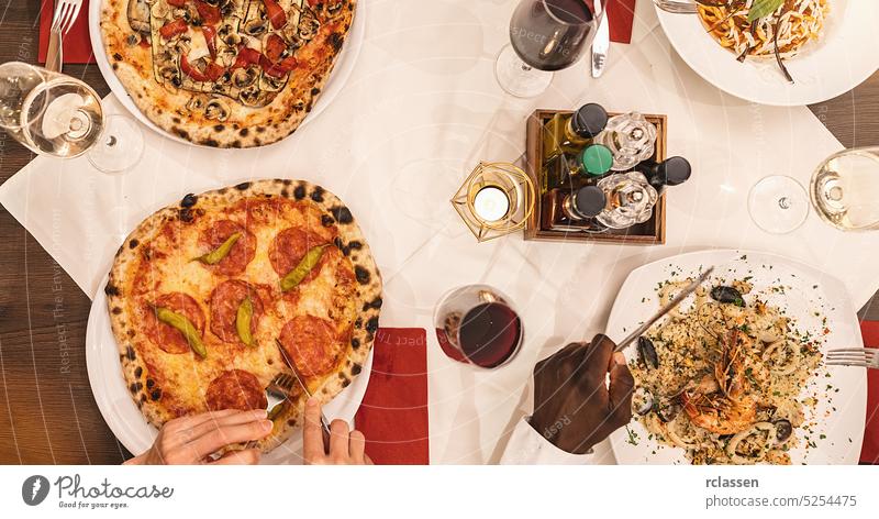 Freunde essen Pasta, Pizza und Wein - Menschen beim Essen in einem Restaurant - Fokus auf den mittleren Tisch - Sommerlicher Lebensstil, Essen und Freundschaft Konzept
