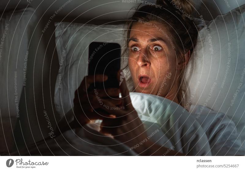 Schockierte Frau mit Smartphone im Bett. Schlaflosigkeit und Stalking Konzeptbild Glück einmaliger Austausch Bettkopfkissen schlafen Schlafstörung Nacht Angst