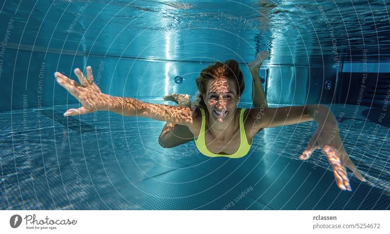 Junge Frau schwimmt unter Wasser im Pool thermisch Resort platschen Lächeln schwimmen Mode schön junges Mädchen Behaarung Sinkflug Glück Feiertag Menschen