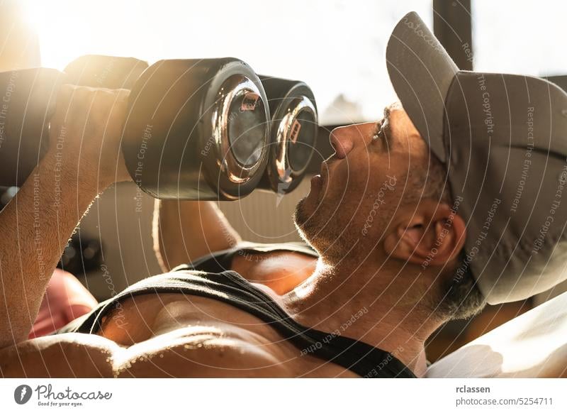 Starker Mann, Bodybuilder beim Training mit Hanteln in einem Fitnessstudio Verschlussdeckel Sonnenlicht passen Sport Übung Gewicht Atelier Unterleib Heben Kraft