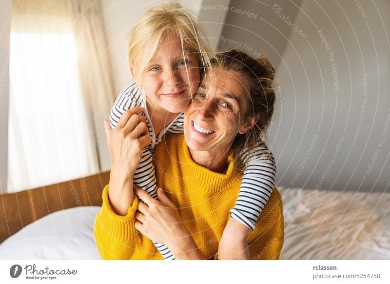 Glückliche Tochter gibt Mutter Huckepack lächelnd in die Kamera. Gute Zeit zu Hause Konzept Bild Huckepackverkehr Mama Familie heimwärts glückliche Mutter Kind