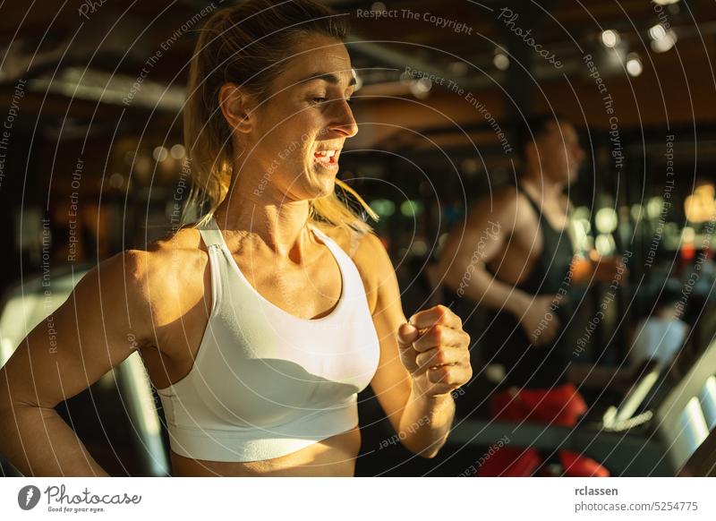 Seitenansicht einer fitten jungen Frau und eines Mannes, die nebeneinander auf modernen elektrischen Laufbändern im Fitnessstudio laufen Lifestyle Maschine